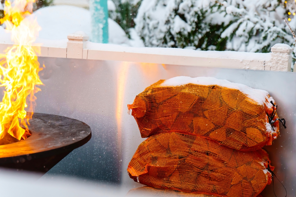 Firewood,in,bags,next,to,round,barbecue,in,winter